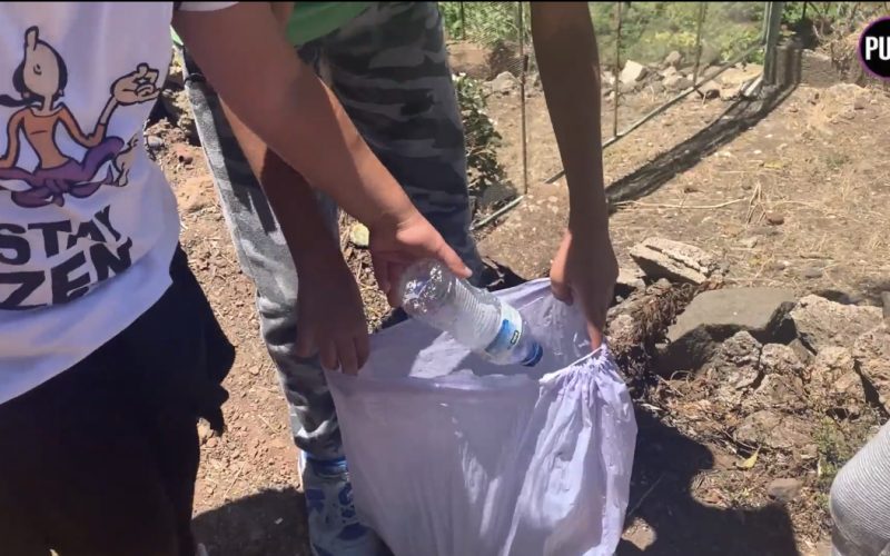 Un scout recoge una botella de plástico