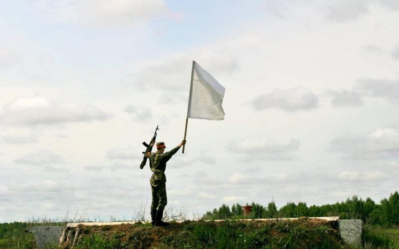 Soldado elevando una bandera blanca